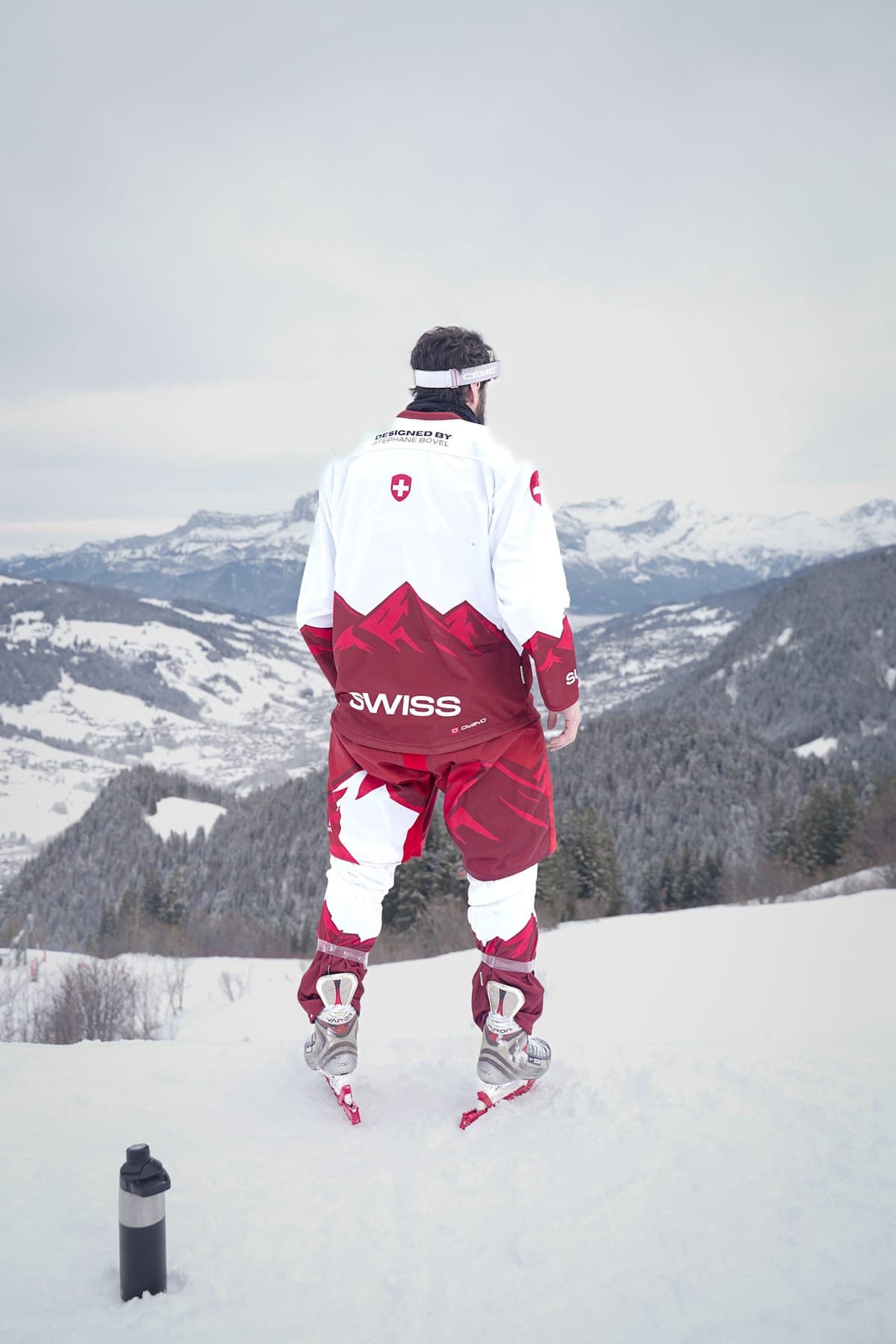 A rider in a red-and-white Swiss suit looking out over the valley