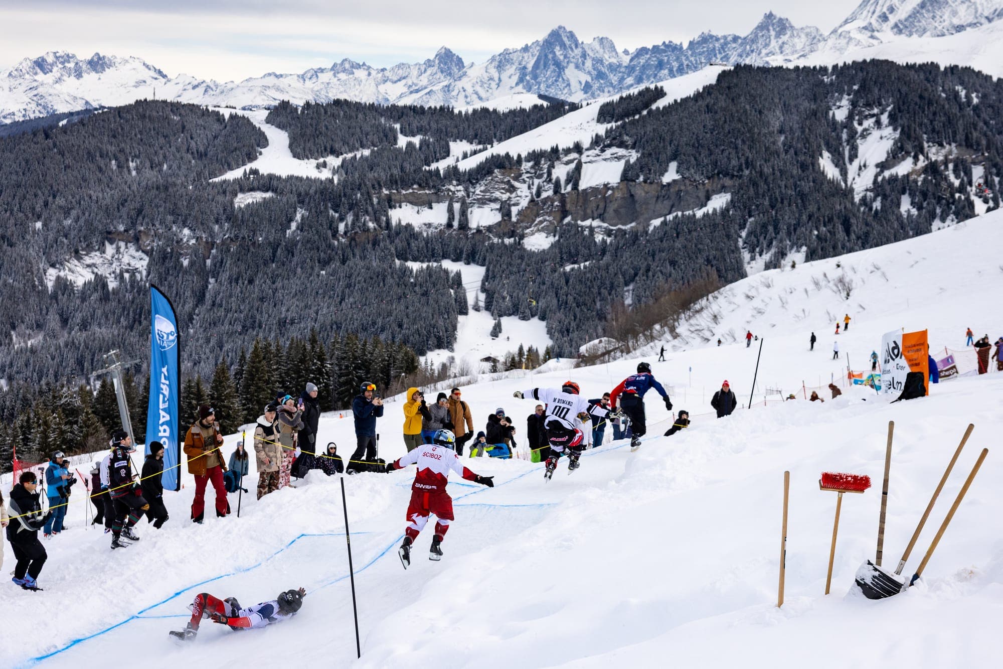 A heat on the slope at Praz-sur-Arly, spectators lining the track and the peaks behind