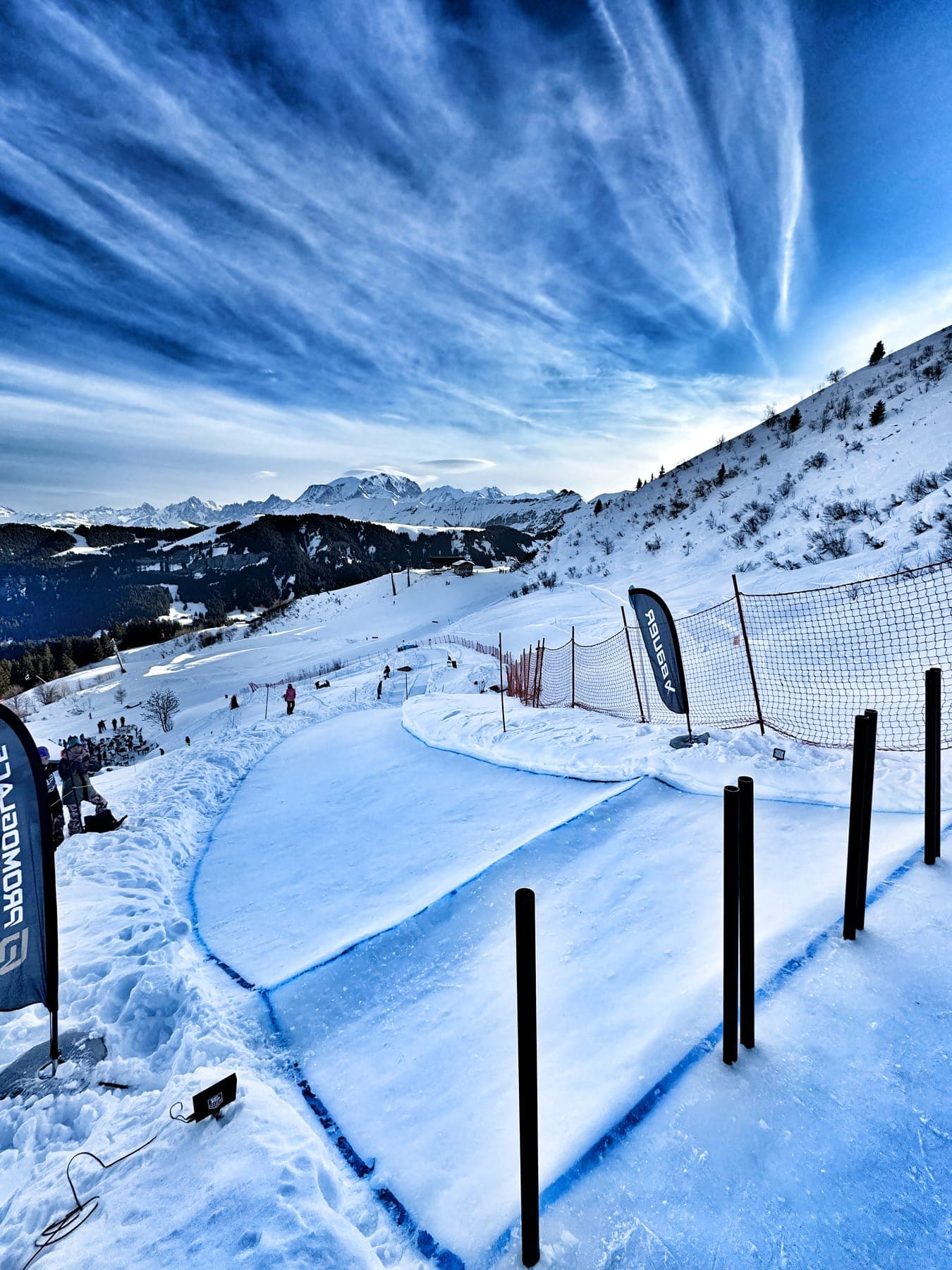 The empty ice track curving down the mountainside under a streaked blue sky