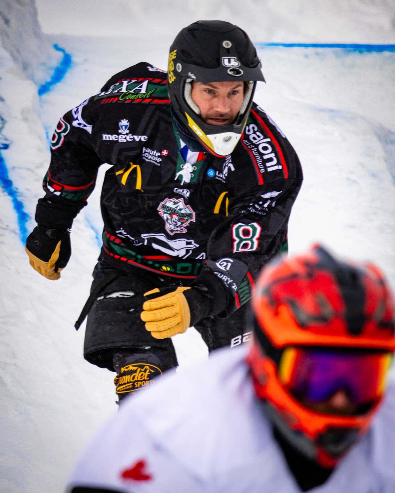 A rider in a black number 8 jersey closing in on another rider in an orange helmet