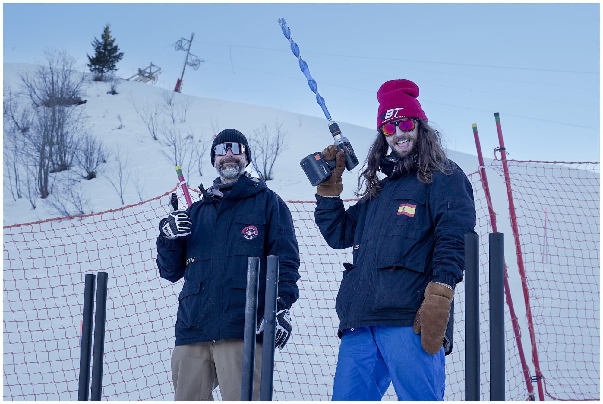 Two track builders posing on the slope with their ice drills